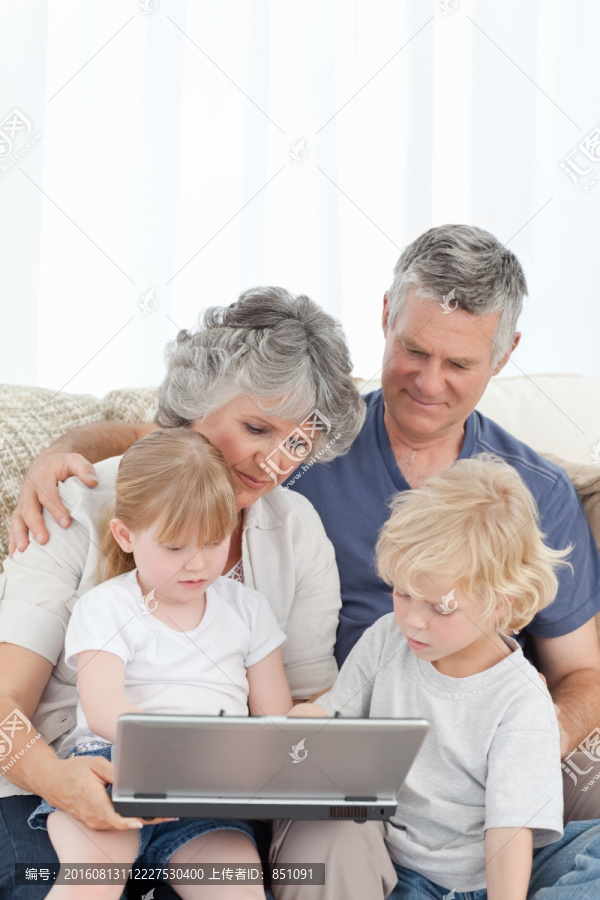沙发上一起玩电脑的祖孙们