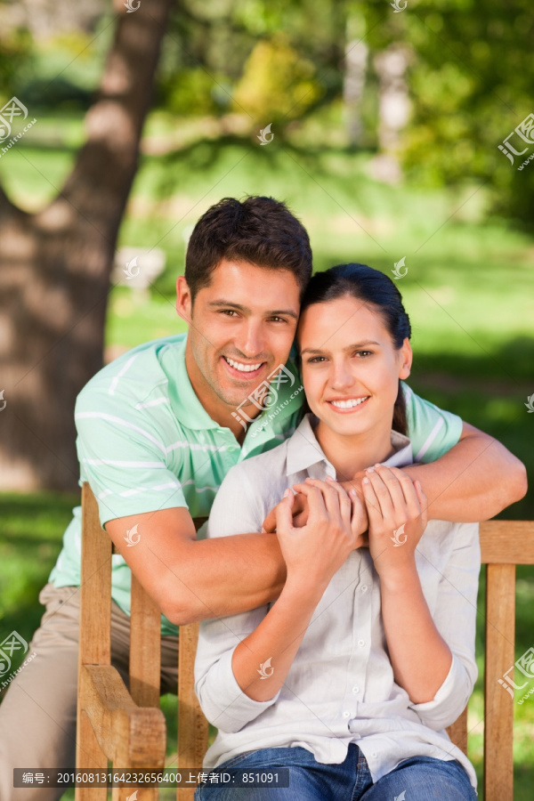 男友环抱着坐着的女友在微笑