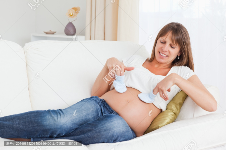 在沙发上玩小袜子的孕妇