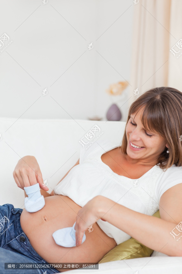 在沙发上玩小袜子的孕妇