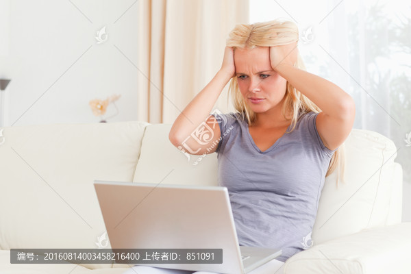 沮丧的女人坐在沙发上使用电脑