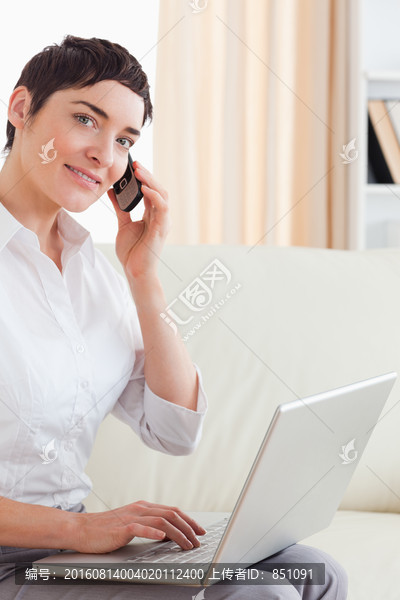 沙发上打电话用电脑的女人