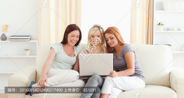 三个女人在沙发上看电脑