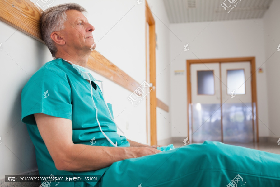 疲倦的外科医生坐在走廊的地板上