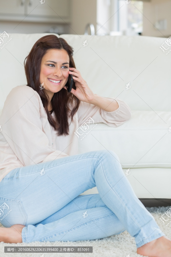 坐在地毯上使用手机的女人
