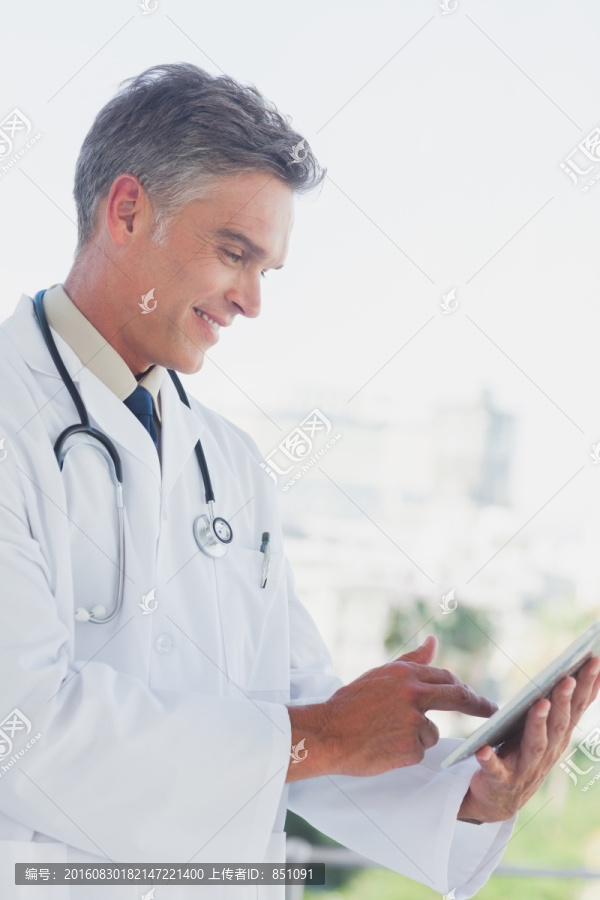 微笑的使用平板电脑的医生