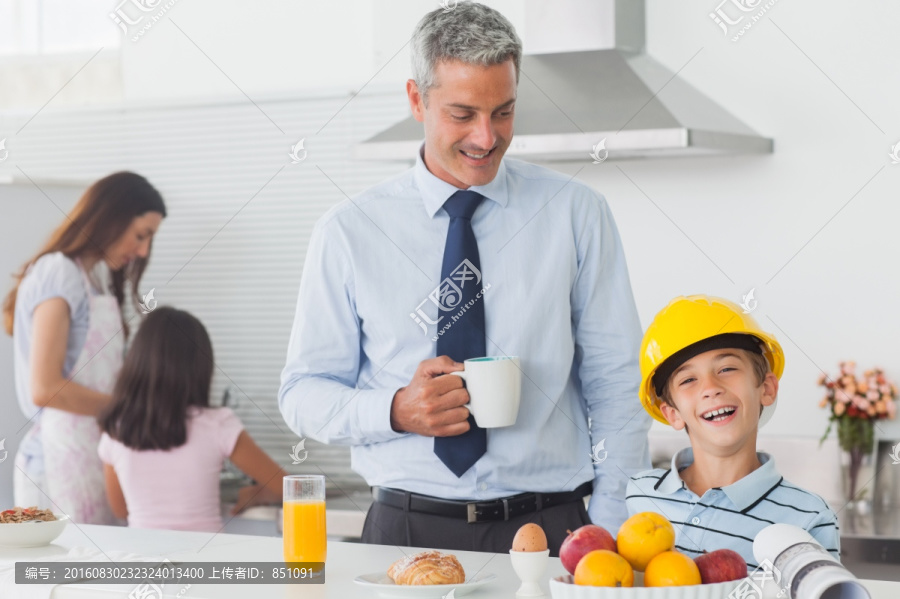 小男孩戴着父亲的安全帽吃早餐