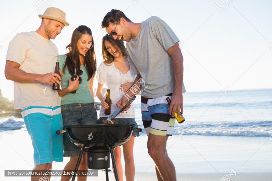 微笑的年轻朋友在海滩上一起烧烤