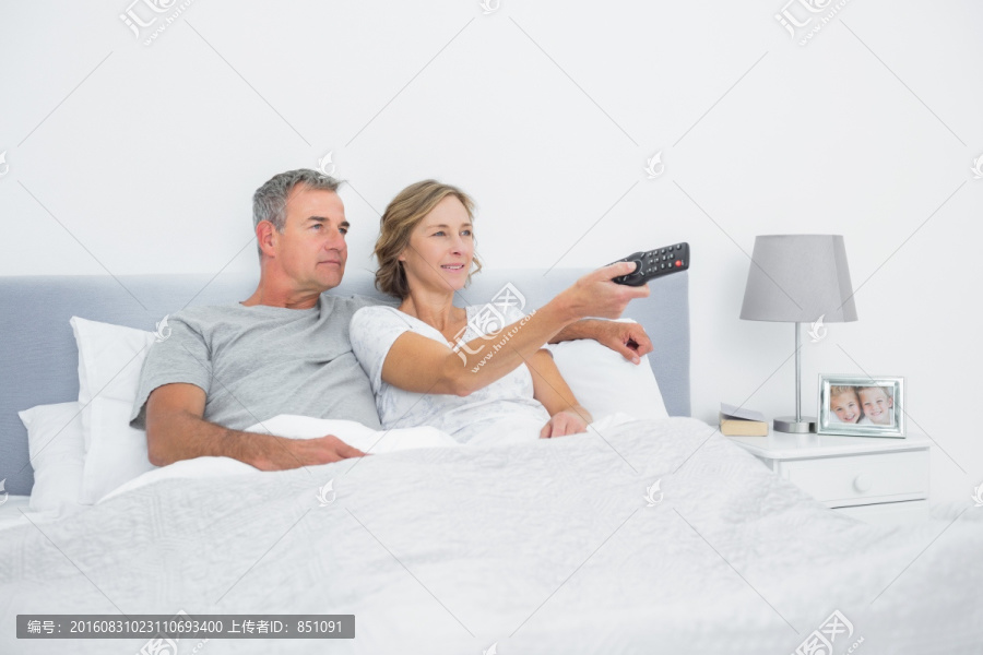 幸福的一对夫妇在卧室里看电视