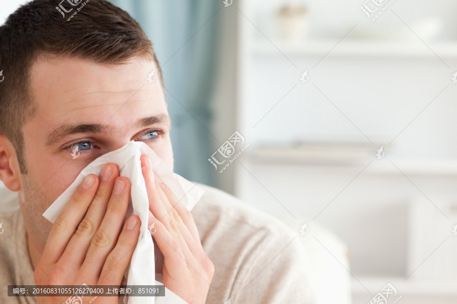 年轻人在客厅用纸巾擤鼻涕