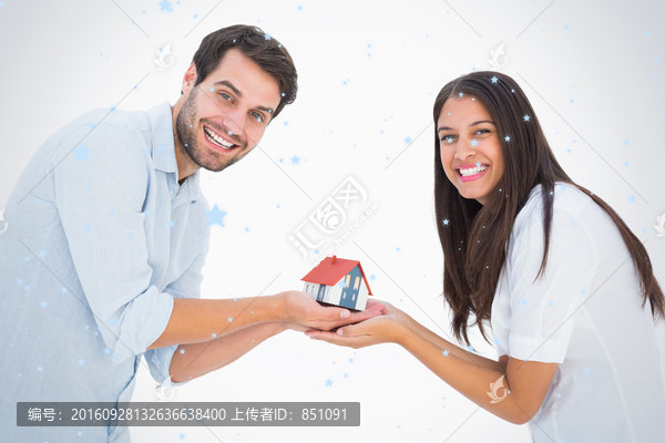 夫婦微笑著捧著房屋模型