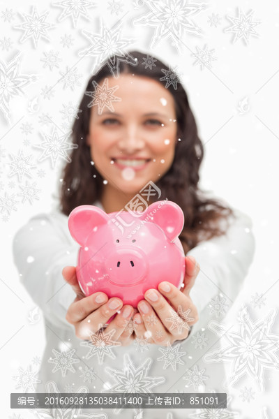 微笑着拿着小猪存钱罐的女人