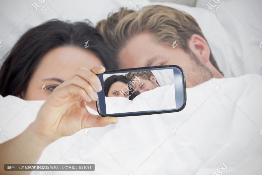 夫妇对着手机自拍的复合形象