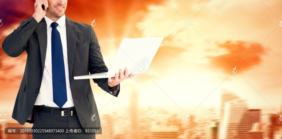 拿著筆記本電腦打電話的商人
