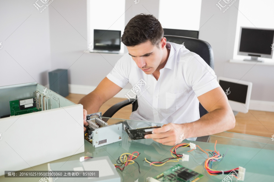 电脑工程师坐在办公桌前看着硬件