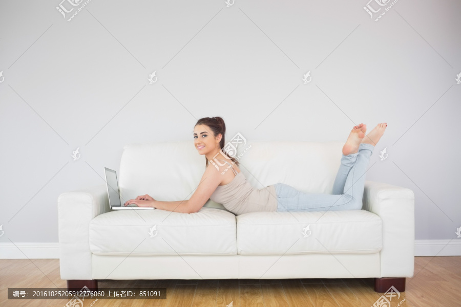 女人趴在沙发上用笔记本电脑
