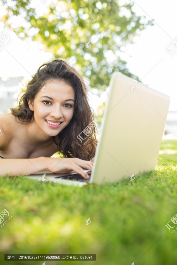 微笑的女人在公園里用筆記本電腦