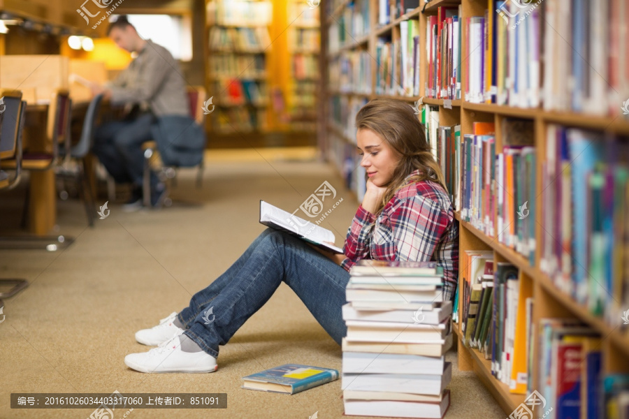 坐在图书馆地板上看书的女大学生