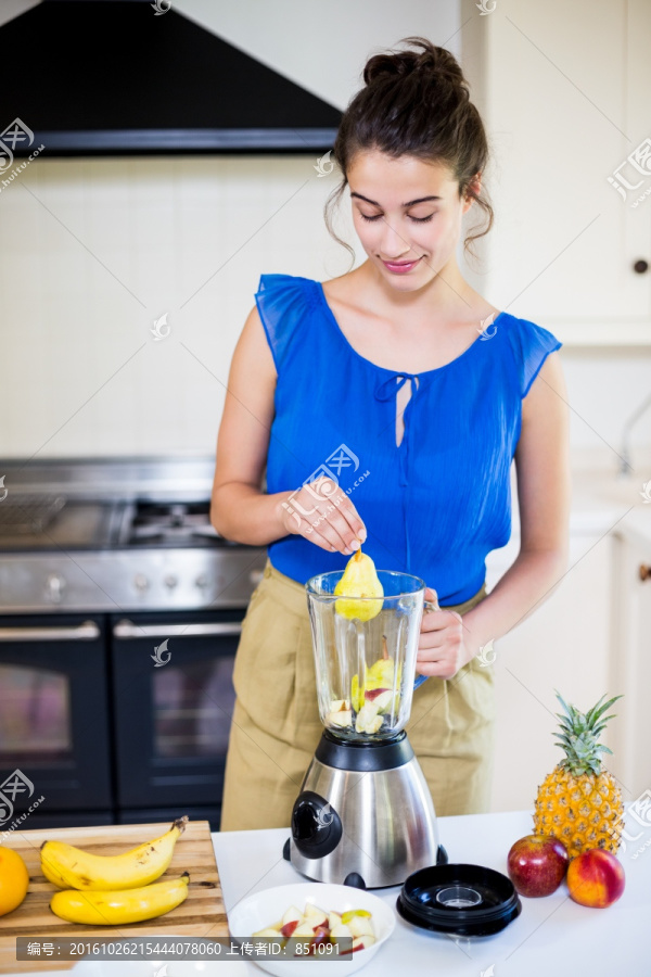 年轻女人在厨房里榨水果