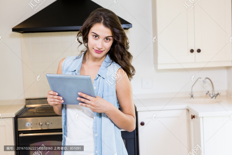 在厨房里使用平板电脑的女人