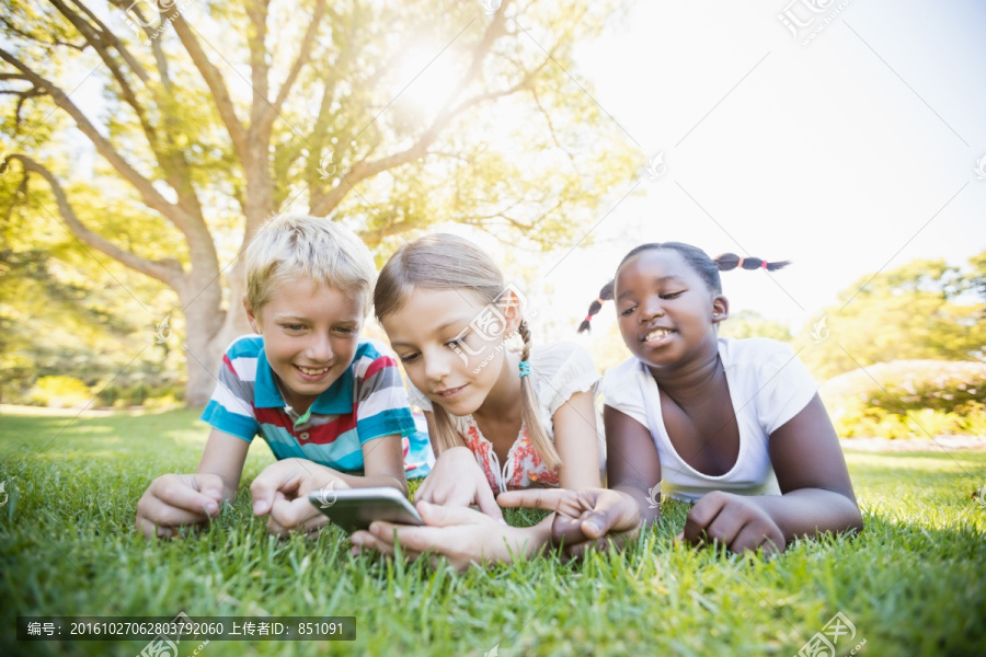 趴在草坪上用手机的小朋友们