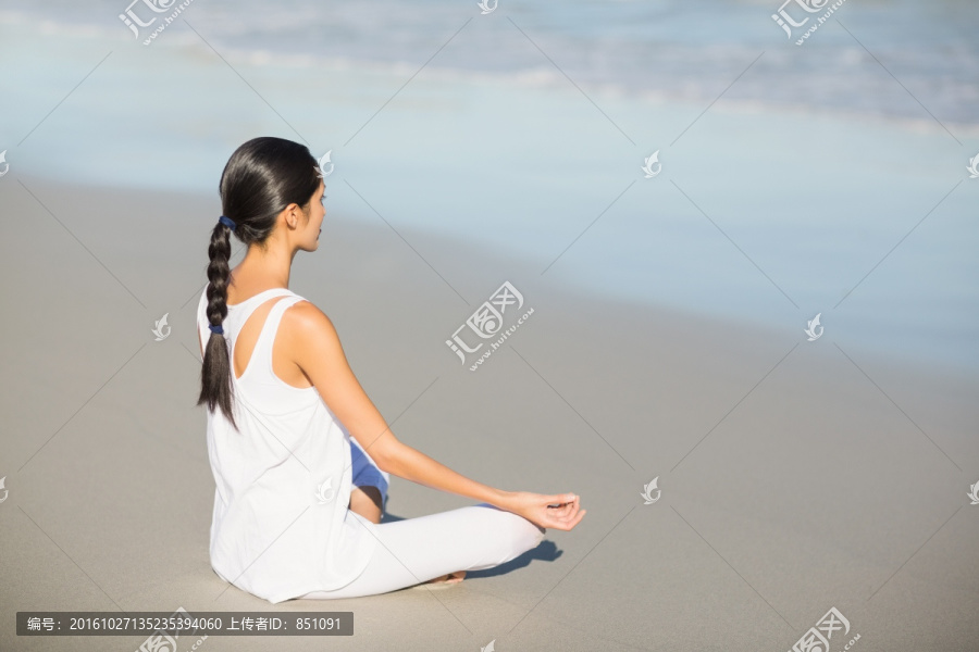 盘腿坐在沙滩上冥想的女人