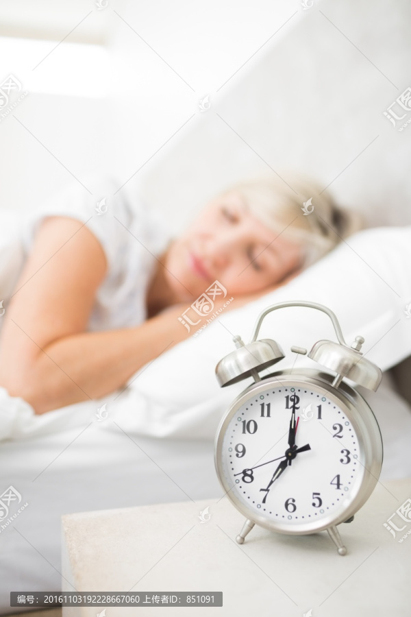 床头柜上的闹钟和躺在床上的女人