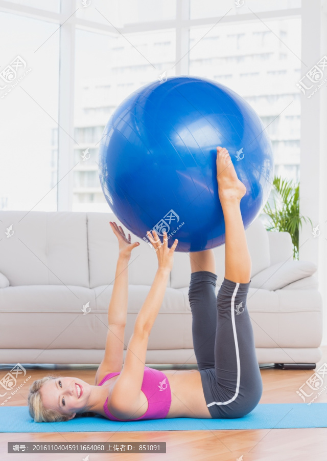 双腿夹着健身球举起的女人