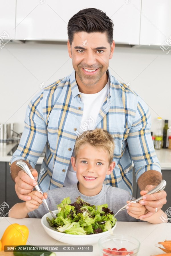 在厨房里教儿子拌沙拉的父亲