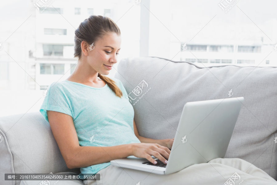 坐在沙发上使用笔记本电脑的女人