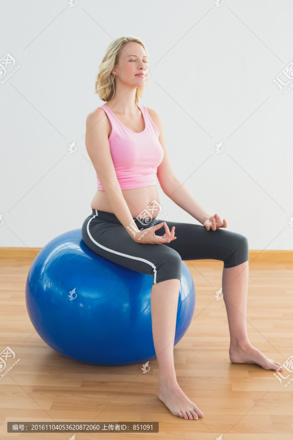 金发孕妇坐在健身球上冥想