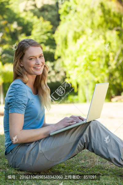 坐在公园里用笔记本电脑的女人