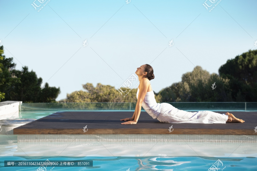 在泳池边做瑜伽的女人
