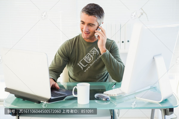 看着笔记本电脑打电话的商务男人