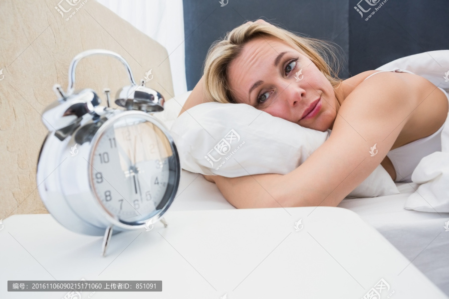 趴在床上的女人看着闹钟
