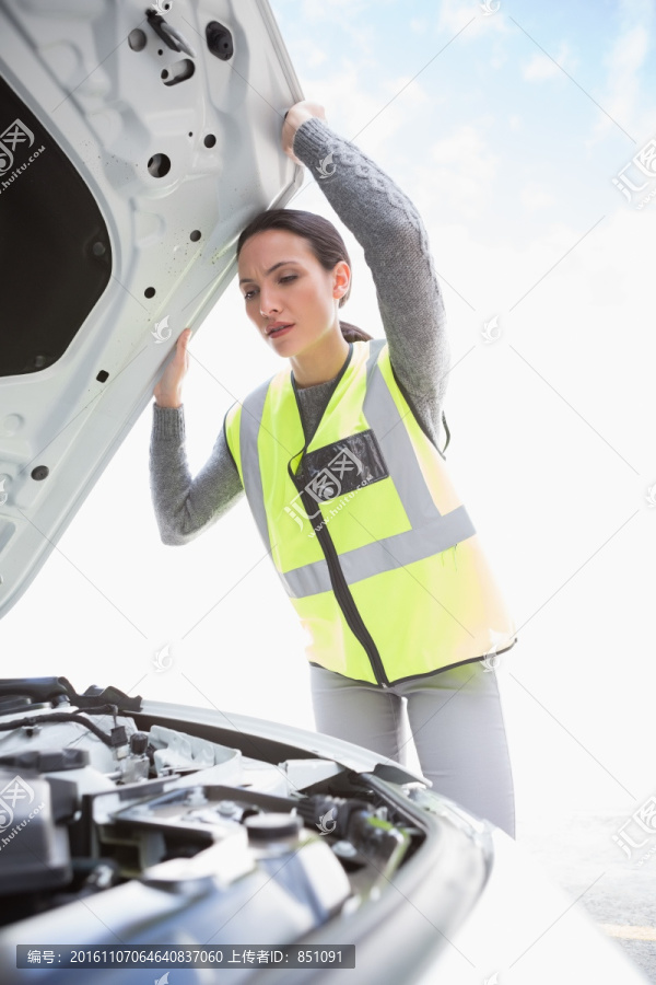 在检查汽车发动机的女人