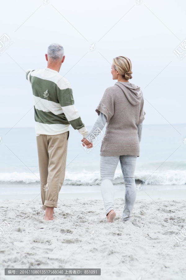 牵着手走在海边的夫妇