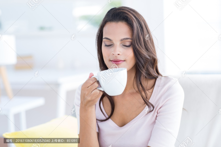 坐在沙发上喝一杯咖啡的女人