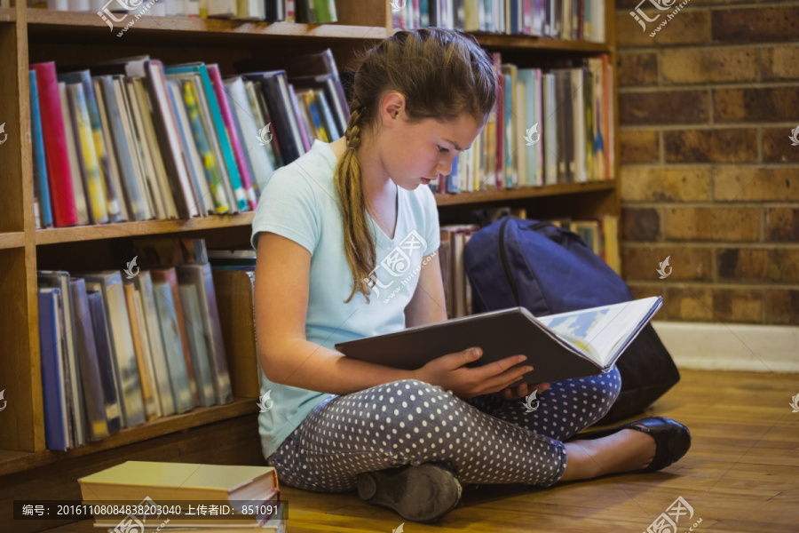 小女孩在图书馆地板上看书