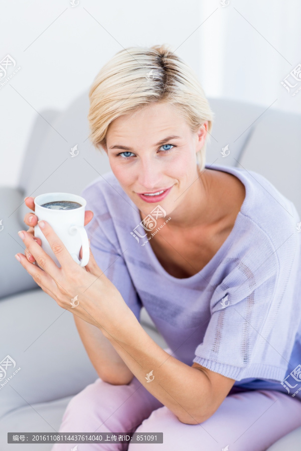 坐在沙发上喝咖啡的金发女人