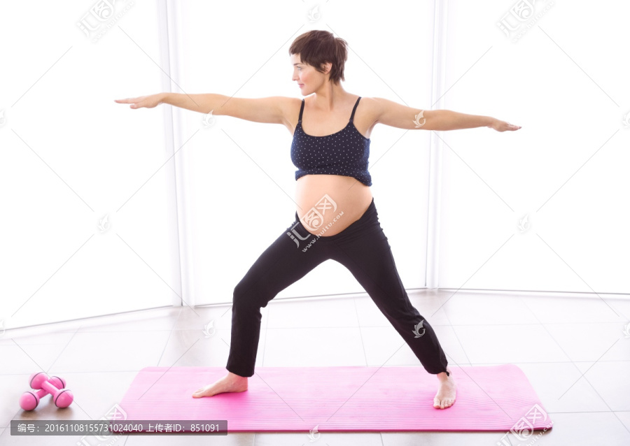 站在瑜伽垫上张开双臂的孕妇