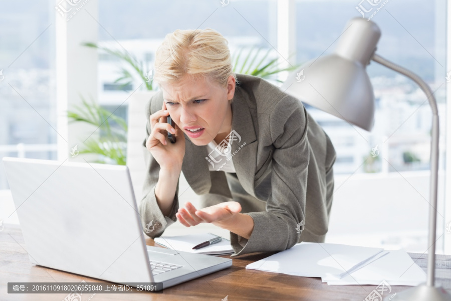 看着笔记本电脑打电话的商务女人