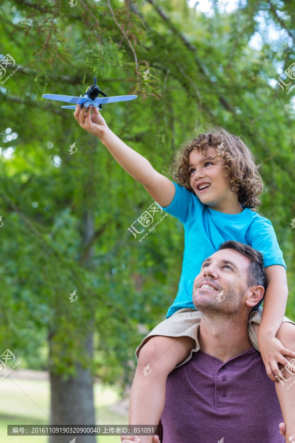 背着儿子在公园里玩飞机的父亲