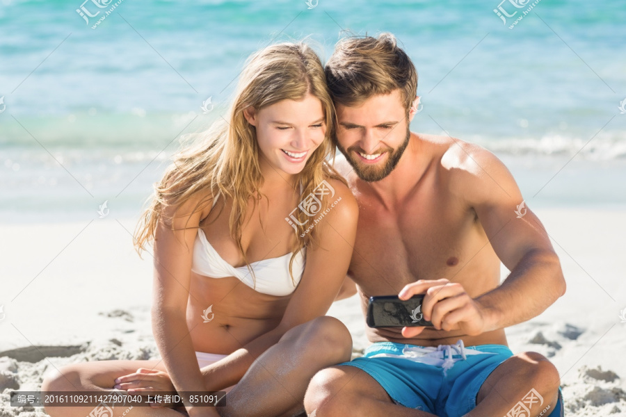 坐在沙滩上拍照的夫妇