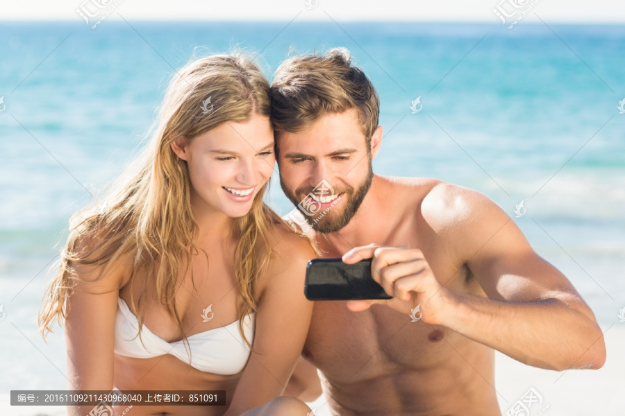 坐在沙滩上拍照的夫妇