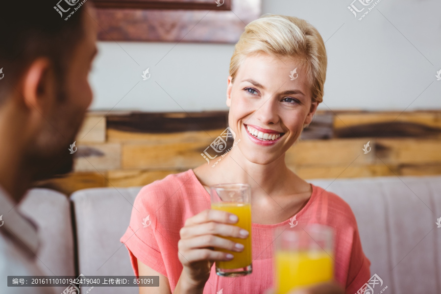 漂亮的金发女郎拿着一杯橙汁