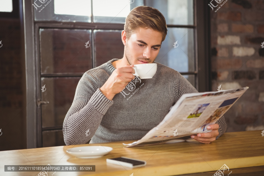 边喝咖啡边看报纸的男人