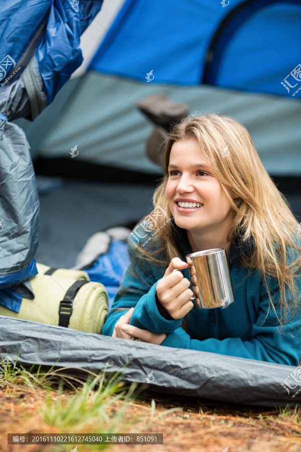 微笑的女人趴在帐篷里喝水