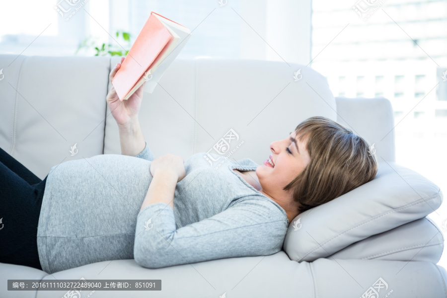 躺在沙发上看书的孕妇