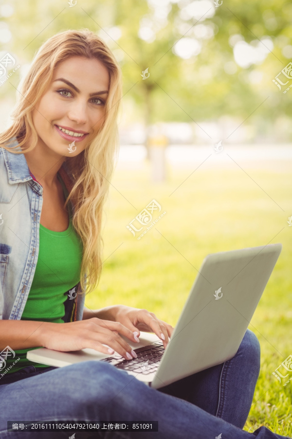 坐在在公园里用笔记本电脑的女人